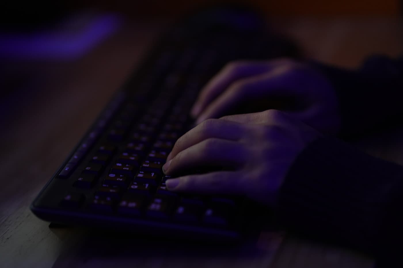Developer's hands on a backlit keyboard, late at night