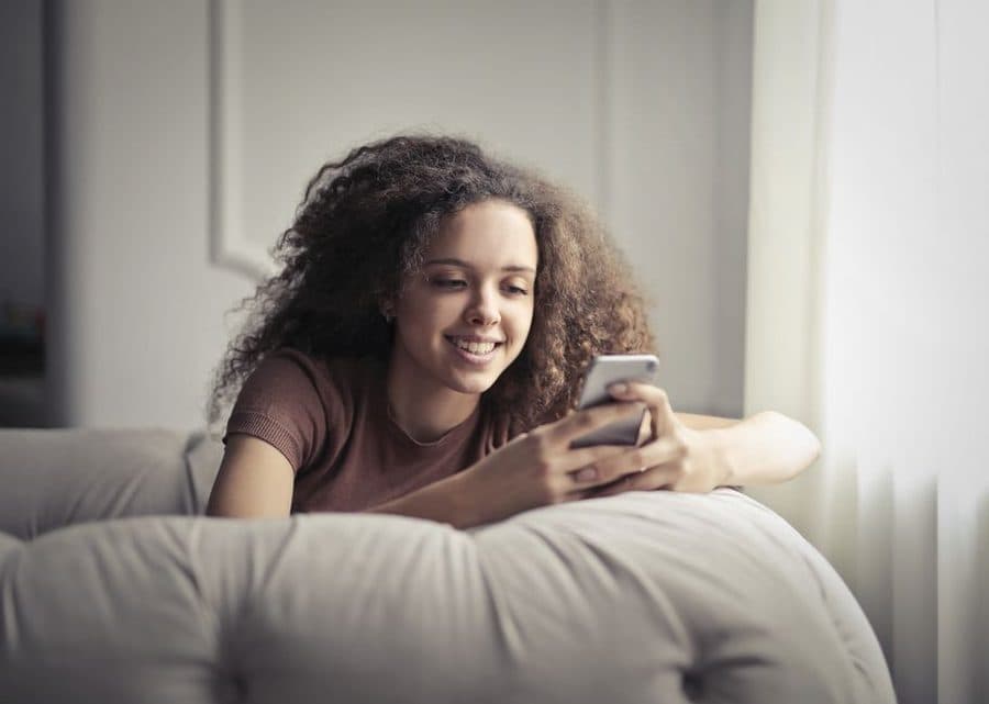 Woman smiling at her phone, relaxed at home
